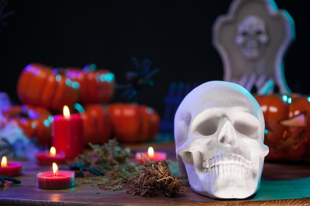 Menacing skull for halloween party sitting on a wooden table with scary pumpkin. Haunted human skull.