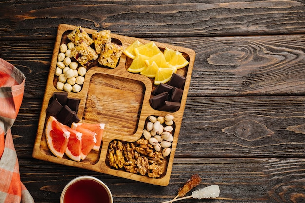 Menazhnitsa on a wooden background delicious tea nuts and chocolate on a wooden square plate