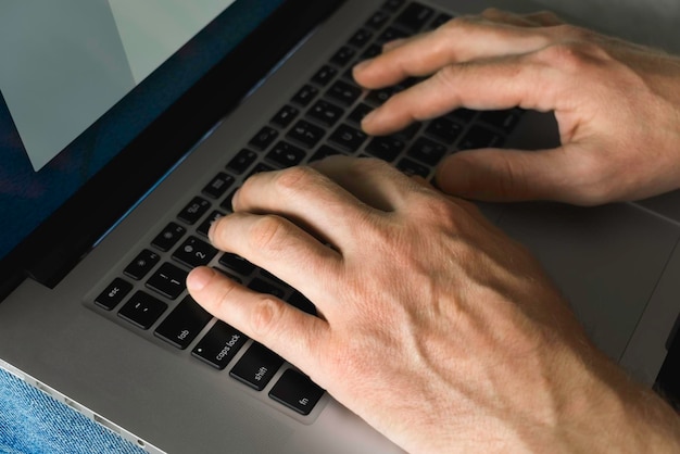 mens hands print on the laptop while working at home closeup