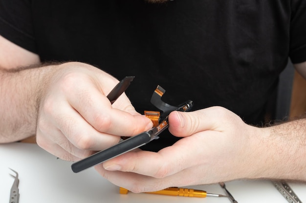 Mens hands repair a mobile phone install spare parts