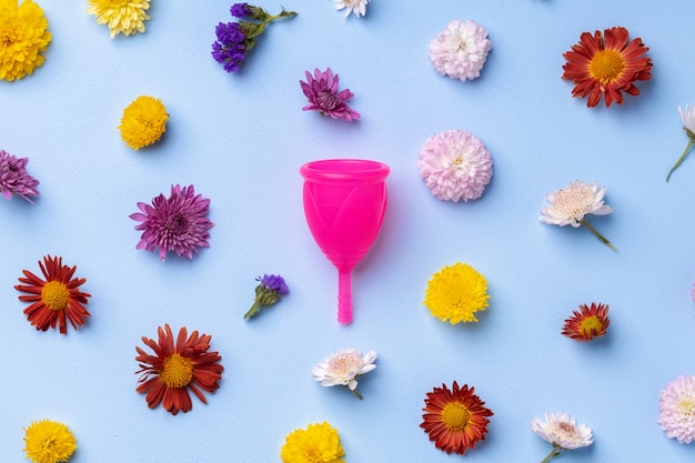 Menstrual cup on floral pattern background top view