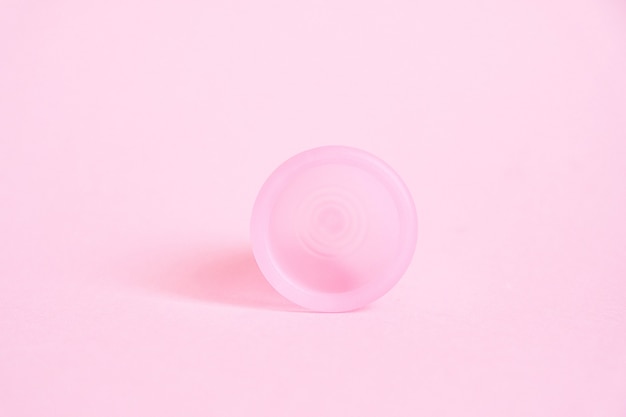 Menstrual cup on pink background. Alternative feminine hygiene product during the period. Women health concept.