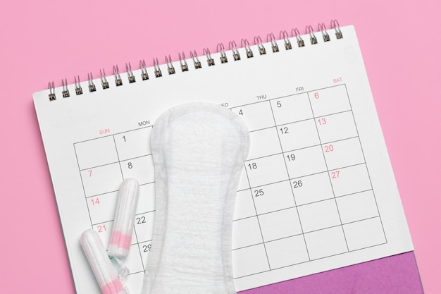 Menstruation calendar Calendar with pads and tampons on a pink background