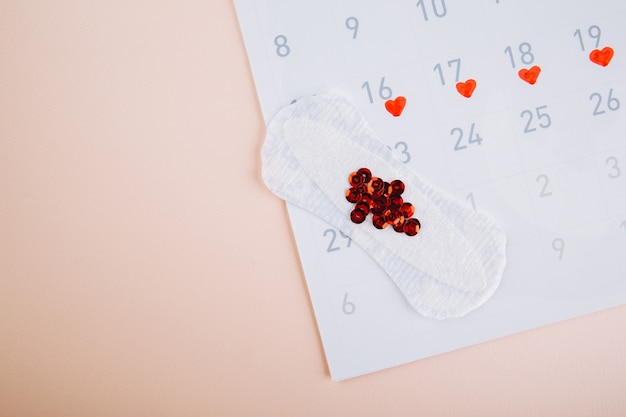 Menstruation calendar with daily sanitary pads on pink background. Woman critical days, woman hygiene protection concept.