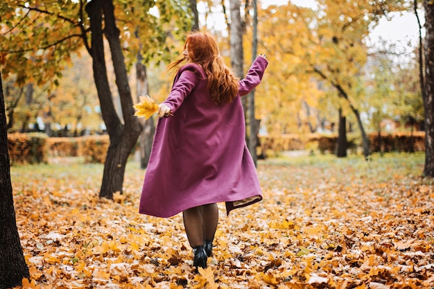 Mental health in autumn happy redhaired woman holding yellow maple autumn leaves