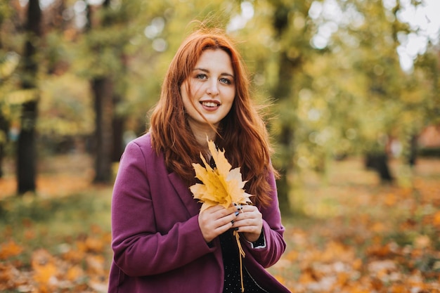 Mental health in autumn happy redhaired woman holding yellow maple autumn leaves