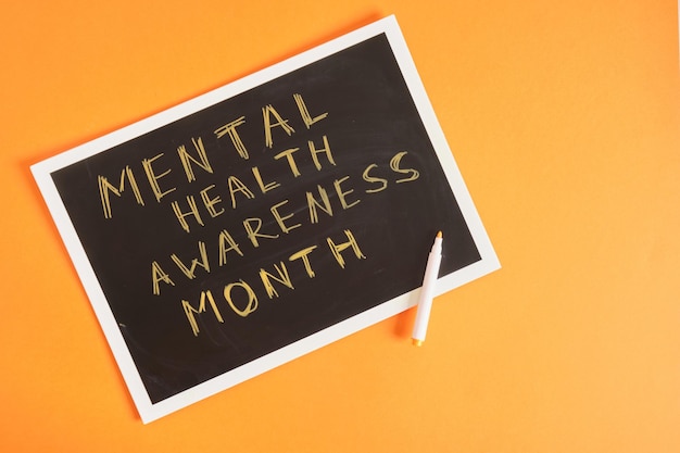 Mental health awareness month text on board orange background