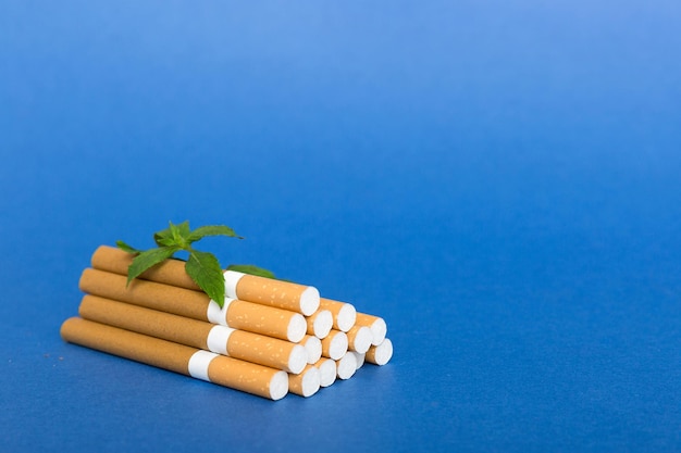 Menthol cigarettes and fresh mint leaves on colored background Many cigarettes stacked together top view flat lay