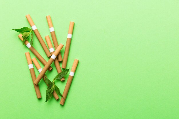 Menthol cigarettes and fresh mint leaves on colored background Many cigarettes stacked together top view flat lay