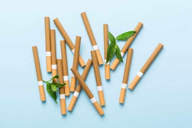 Menthol cigarettes and fresh mint leaves on colored background Many cigarettes stacked together top view flat lay