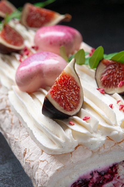 Meringue roll with cherry jam Decorated with greenery and fig slices Dark background