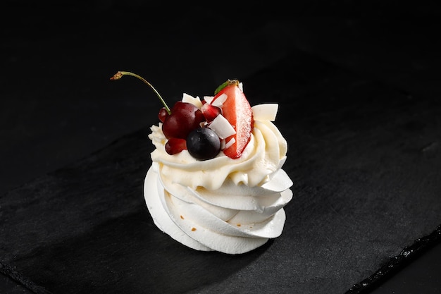 Meringue with berries on top on black background