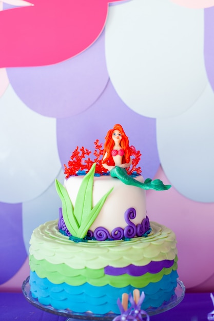 Photo mermaid theme cake with colorful glitter tails, shells and sea creatures toppers