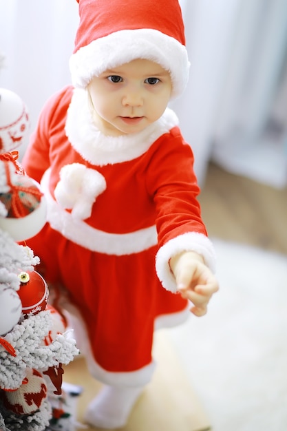 Merry bright christmas. Lovely baby enjoy christmas. Childhood memories. Santa girl little child celebrate christmas at home. Family holiday. Girl cute child cheerful mood play near christmas tree.