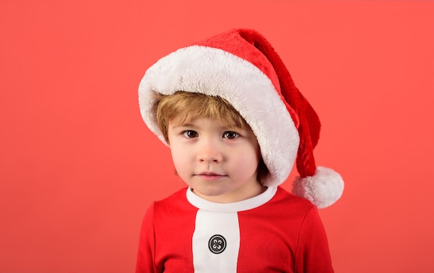 Merry christmas christmas kid in red hat new years holiday little boy in santa claus hat christmas