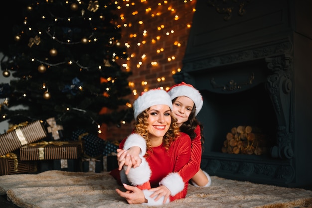 Merry Christmas and Happy Holidays! Beautiful mother with little daughter in Christmas costumes spend time together near the Christmas tree.