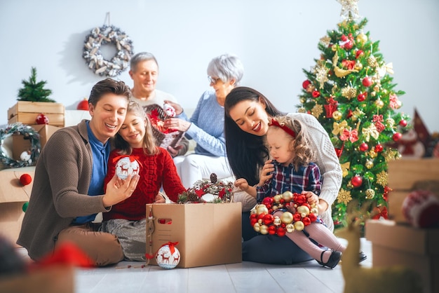 Merry Christmas and Happy Holidays!  Grandparents, mother, father and children decorate the tree in room. Loving family indoors.