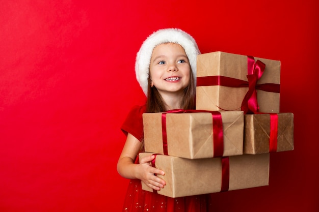 Merry Christmas and happy holidays Portrait of  emotional girl in a Santa cap on a red background