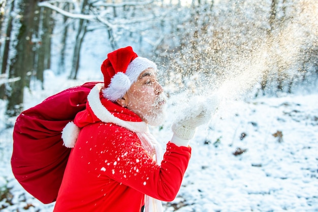 Merry Christmas and happy holidays. Santa blowing snow - face close up.