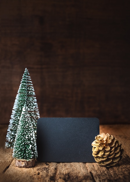 Merry Christmas and happy new year on blackboard with tree and gold pine cone on wood table and wall