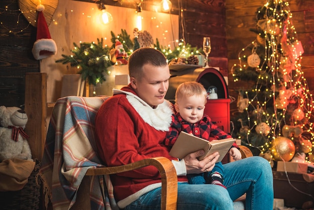 Merry Christmas and Happy new year Christmas scene Father is reading the book for his baby son Famil