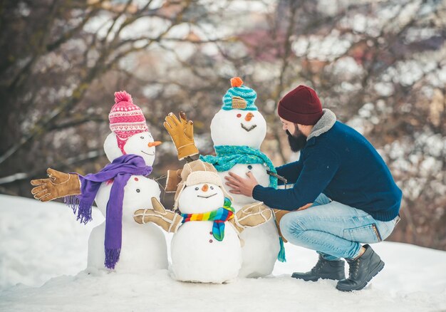 Photo merry christmas and happy new year enjoying nature wintertime snowman and funny bearded man in the s