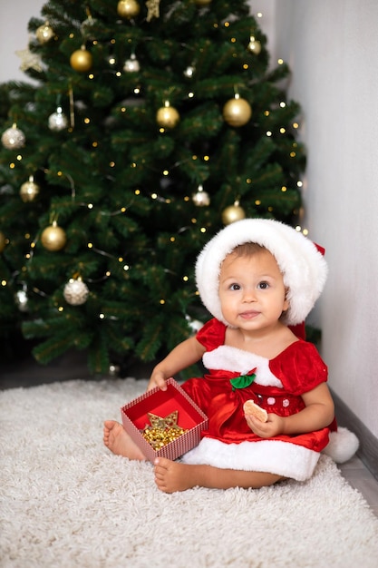 Merry Christmas Portrait of a cute little oneyearold girl baby in a cozy bedroom dressed up for the holiday Lifestyle