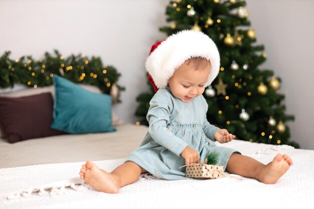 Merry Christmas Portrait of a cute little oneyearold girl baby in a cozy bedroom dressed up for the holiday Lifestyle