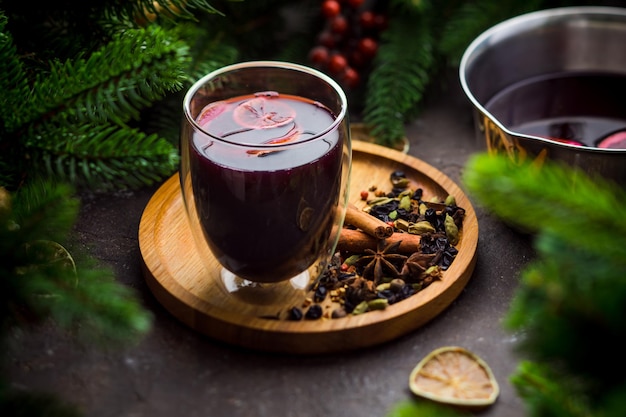 Merry Christmas thermo glass with mulled wine and spices fir tree branches on a light wooden plate home cozynes and comfort concept Seasonal winter holidays with traditional tastes and flavours