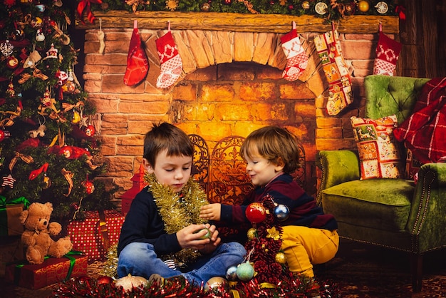 Merry Christmas. Two Caucasian blond boys playing with Christmas decorations at home