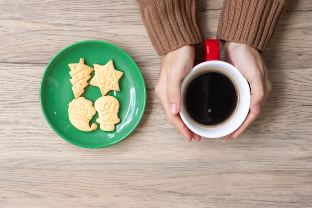 Merry Christmas with woman hand holding coffee cup and homemade cookie on table Xmas eve party holiday and happy New Year concept