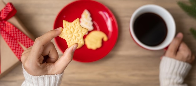 Merry Christmas with woman hand holding coffee cup and homemade cookie on table Xmas eve party holiday and happy New Year concept