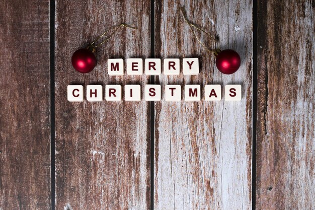 Merry Christmas written with letters of a game and Christmas ornaments on a wooden background