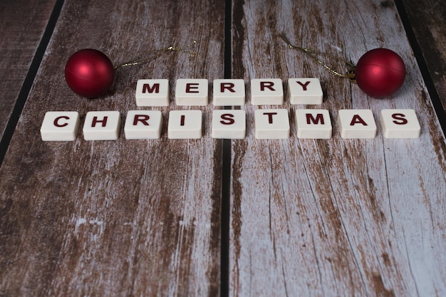 Photo merry christmas written with letters of a game and christmas ornaments on a wooden background