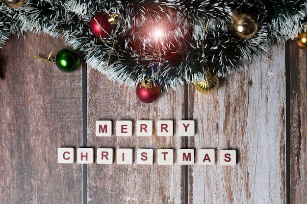 Merry Christmas written with letters of a set and Christmas ornaments with sparkle on a wooden background