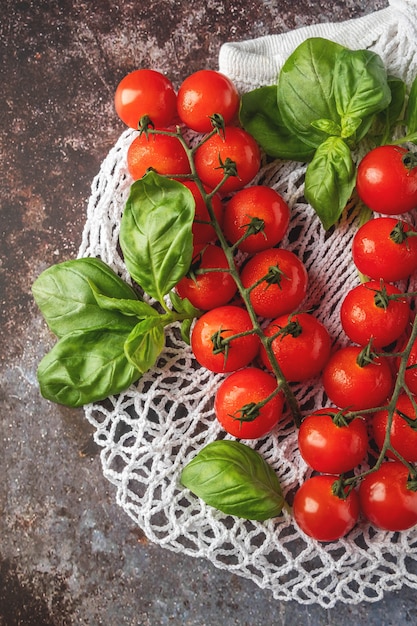 Mesh shopping bag with tomatoes and basil. Plastic free, reuse concept. Flat lay, top view. 