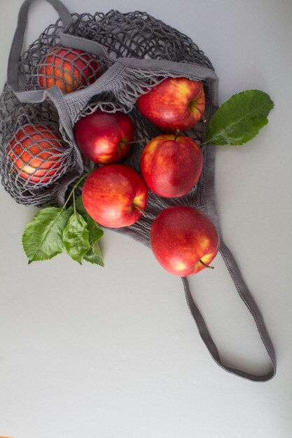 Mesh shopping black bag with red apples on the gray backgroundNo plastic bag concept Top view Location vertical