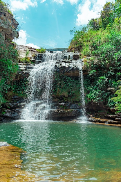 Mesmerizing vertical shot of a waterfall in a jungle full of cliffs and green beautiful leaves