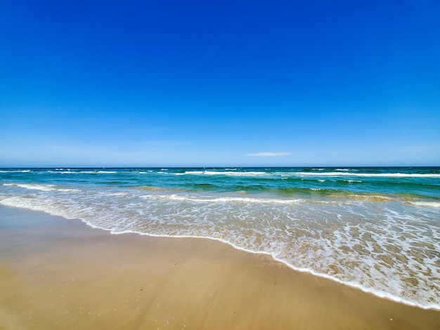 Mesmerizing view of foamy waves rushing into the sandy shore; heaven on Earth