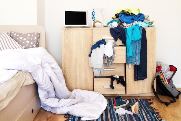 Mess in a teenager's room Clothes are strewn across the chest of drawers floor