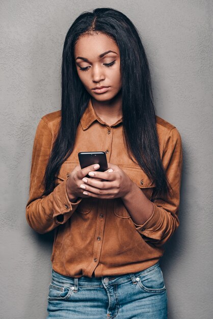 Message for him. Beautiful young African woman holding smart phone and looking at it 