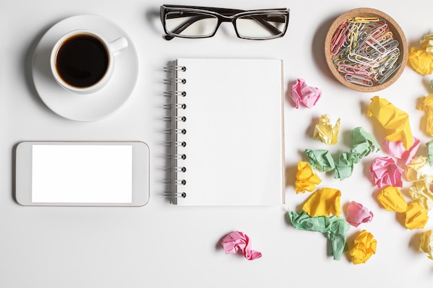 Messy office table with empty smartphone