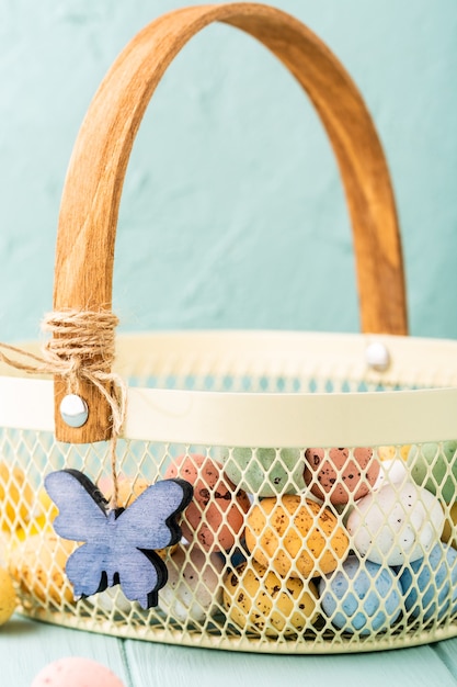 Metal basket with colourful Easter quail eggs. Spring holidays concept with copy space