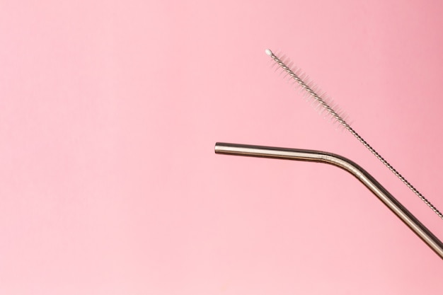 Metal, bendy drinking straw and steel cleaning brush on pink