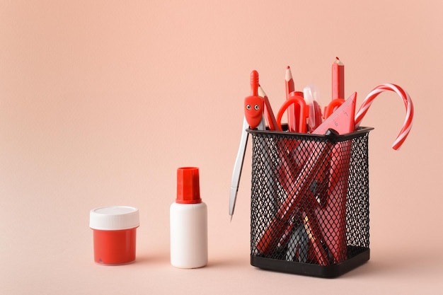 Metal black jar with red pens paints and pencils on a pink background School supplies space for copying