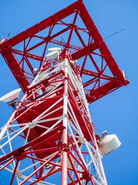 Metal communication mast with satellite dishes Bottom view of communications tower against blue sky Background