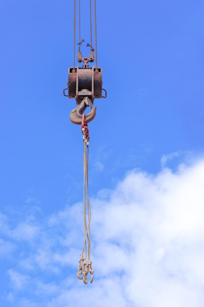 Photo metal crane hook against the background of the blue sky with the clouds