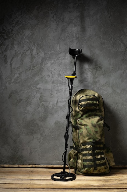 Metal detector and backpack on dark gray background