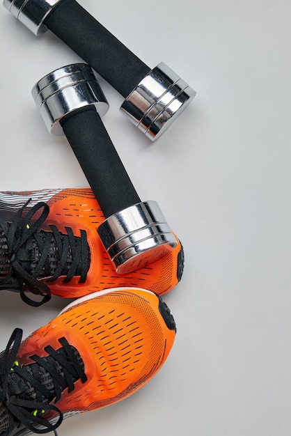 Metal dumbbell fell on the feet of an athlete in orange sneakers Safety precautions when training with heavy equipment