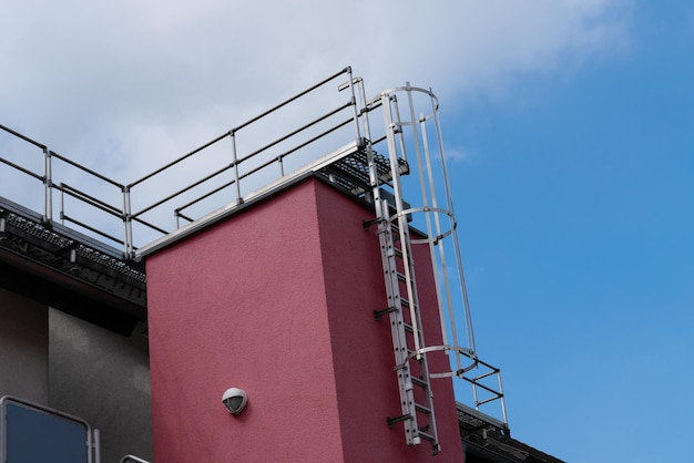 Photo a metal fire escape ladder is attached to a red building the ladder is surrounded by a metal cage a